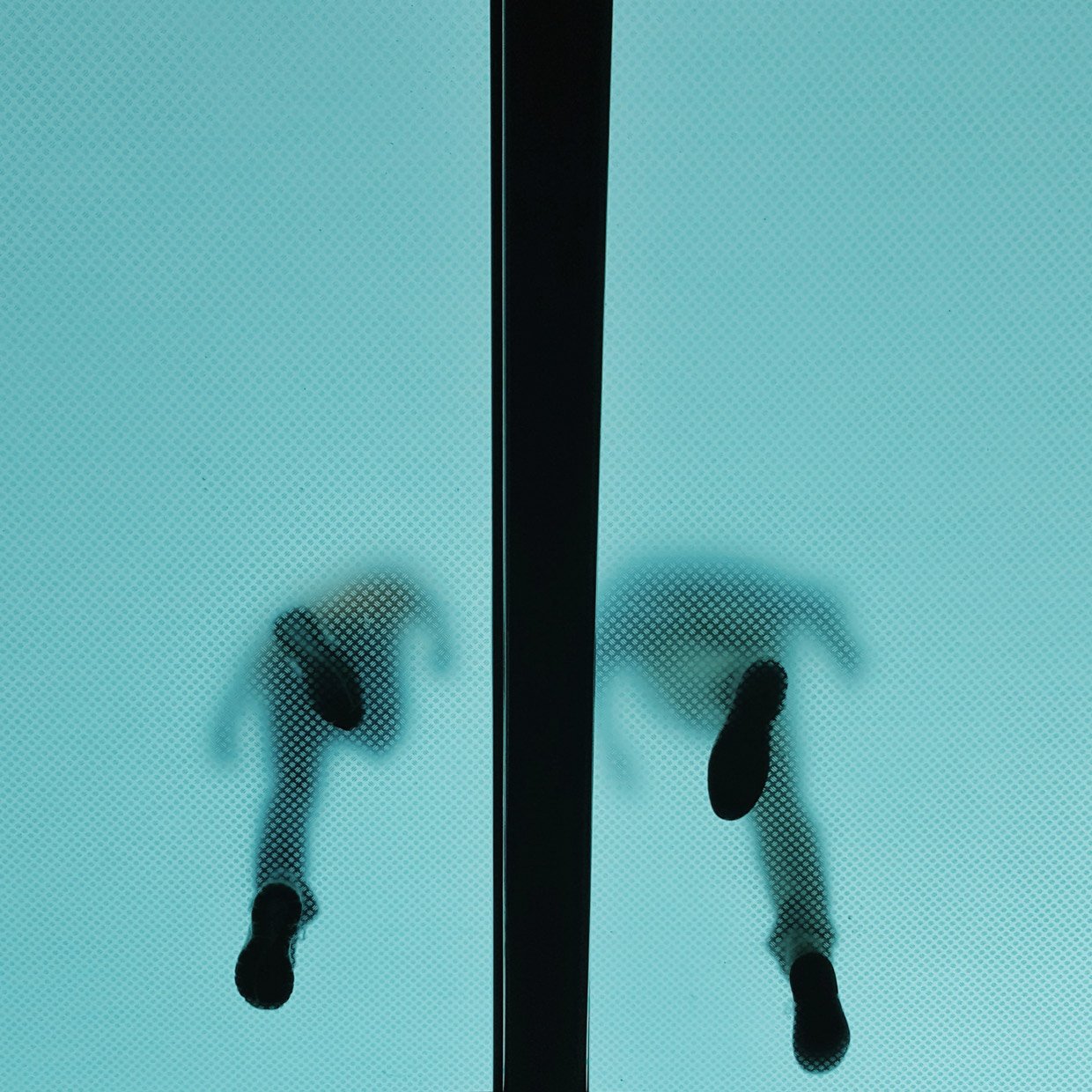 An image of two people walking across a bridge, the camera is looking up so you can see their footprints